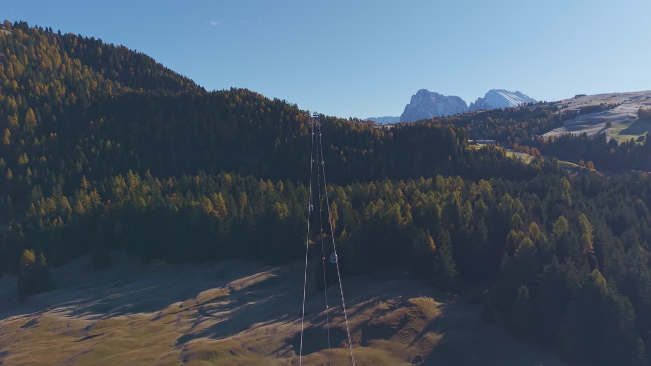 Záběr dronem na lanovku s panoramatickou slunečnou krajinou v Dolomitech