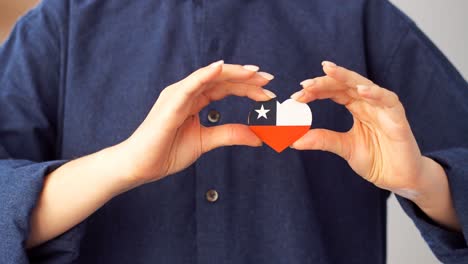 la chica tiene en sus manos un corazón en forma de bandera de chile.