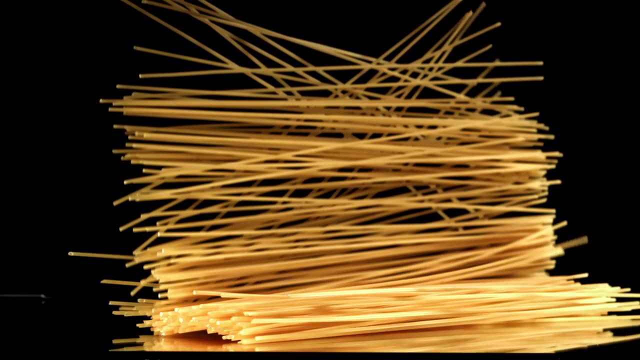 Spaghetti crudi che cadono al rallentatore su sfondo nero