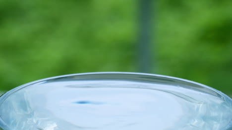 close-up of tiny droplets of water creating ripples and waves in a glass full of water