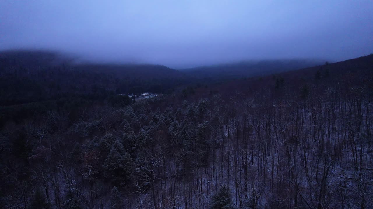 Aerial drone video footage of magical foggy night in the snowy Appalachian mountains during winter, in the Catskill Mountains sub-range