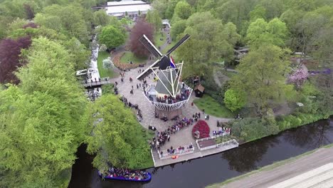 A drone shot of a Dutch windmill with people around it, panning left and up, in the Netherlands
