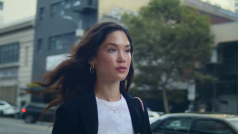 stylish lady walking city street. asian businesswoman going meeting on sidewalk.