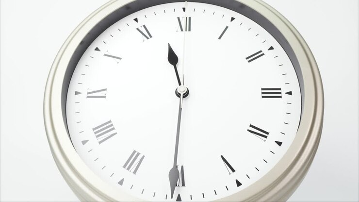 Time lapse silver wall clock tells the time 12 o'clock.