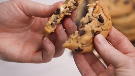 rompiendo una galleta con trocitos de chocolate caliente, trocitos de chocolate pegajosos separando con dos manos cerca de cámara lenta 4k