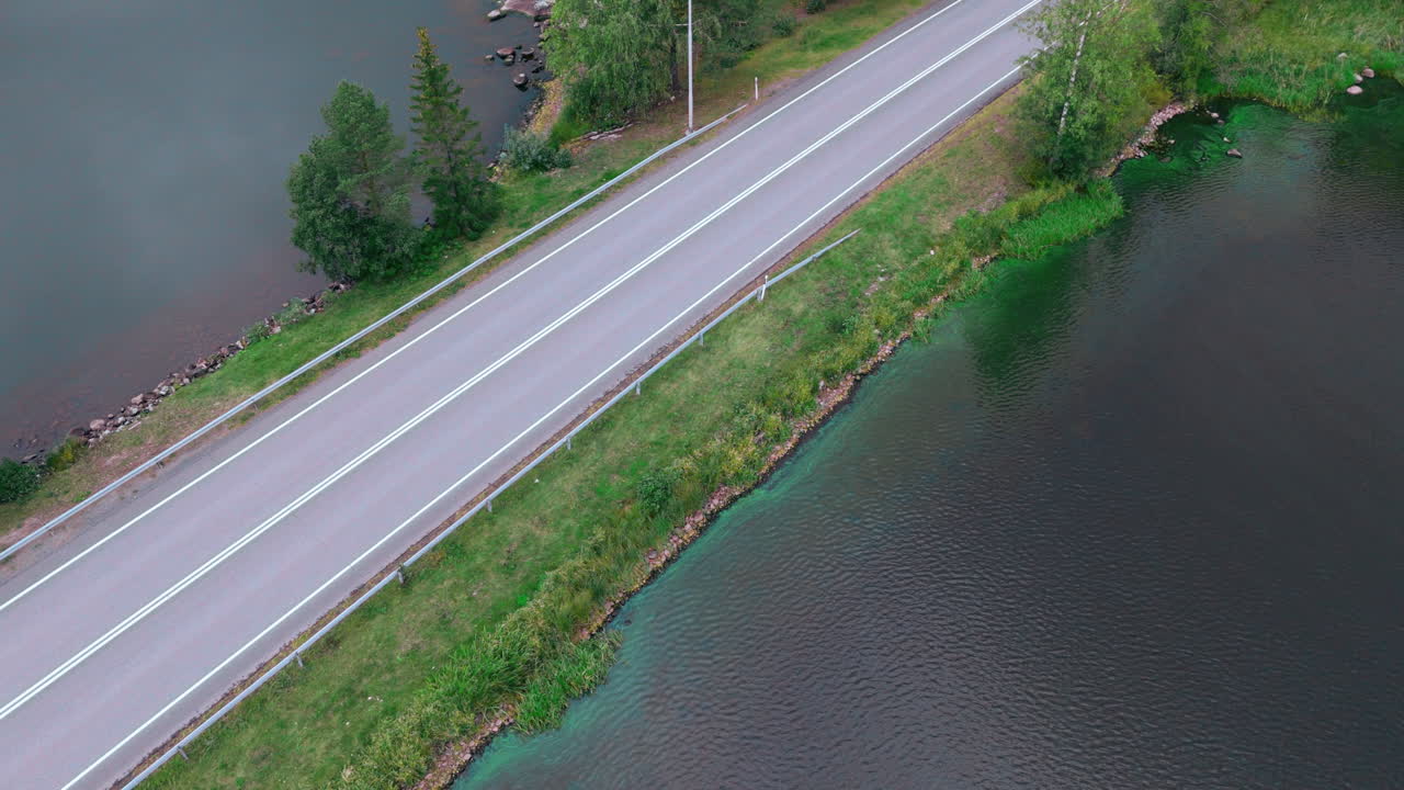 호수를 가로지르는 도로 다리, 바위, 시아노박테리아, 물 속의 파란색-녹색 조류의 대각선 높은 각도 촬영