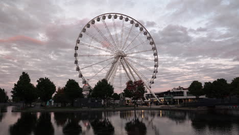 Grande-Roue-De-Montreal---Noria-Girando-Con-Reflejo-En-El-Agua-Durante-La-Puesta-De-Sol-En-El-Antiguo-Puerto-De-Montreal-En-Quebec,-Canadá---Brote-De-Pandemia-De-Coronavirus