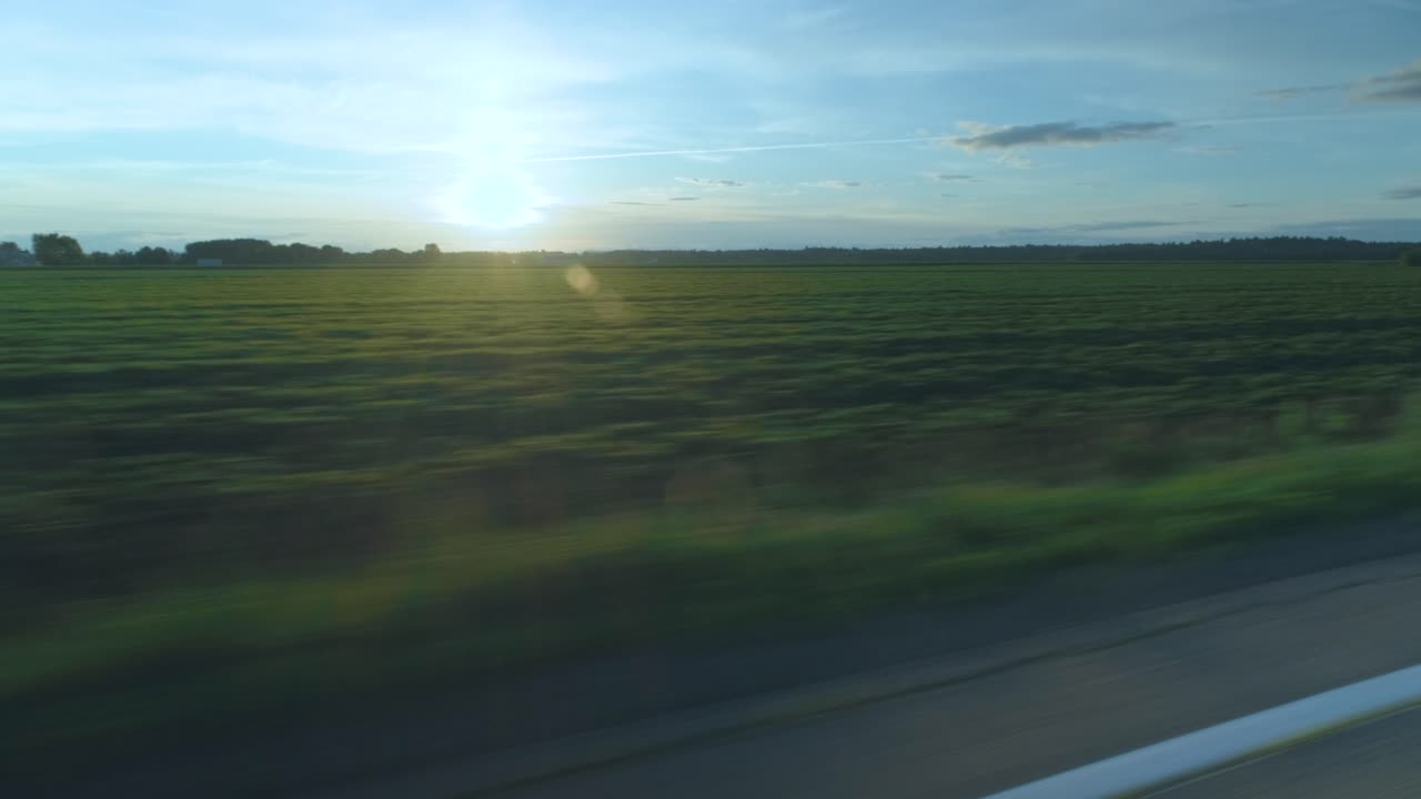 Shot from a speeding car facing an empty countryside field with beautiful flares in Lanaudière, Québec