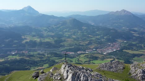 aerial drone view of a large iron cross on top of a mountain in the basque country