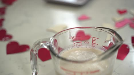 Slow-pan-showing-a-cup-of-almond-milk-in-a-measuring-cup-making-a-special-valentine's-day-cake-vegan-chocolate-cake-eggless-plant-based-dairy-free