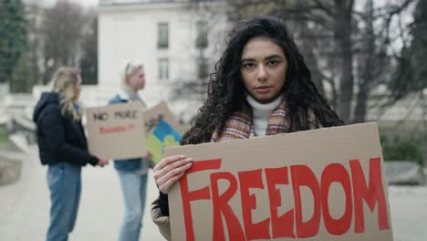 joven mujer caucásica de pie con una pancarta manifiesta en cartón