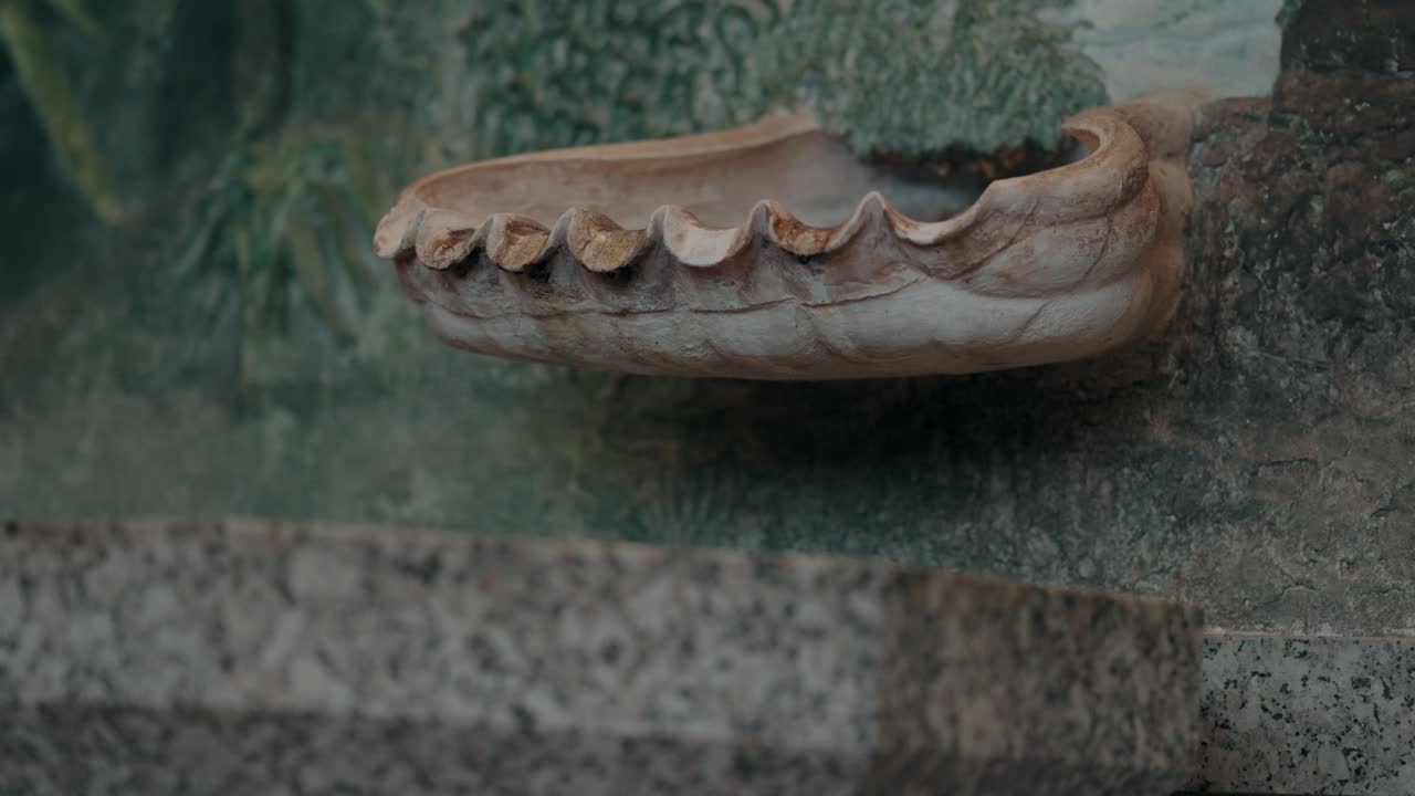 Ornate stone water basin for baptism with carved details on textured wall