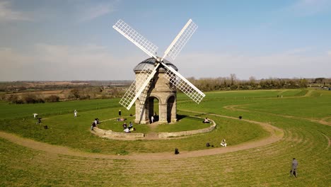 tourists enjoying sunny chesterton windmill aerial low orbit left view over picturesque english rural countryside farmland