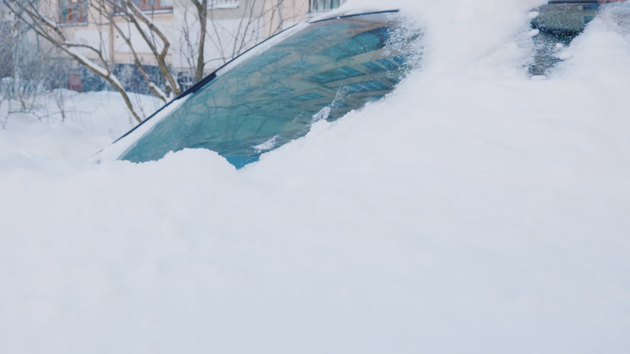 여자가 차에서 눈을 치우고 있다