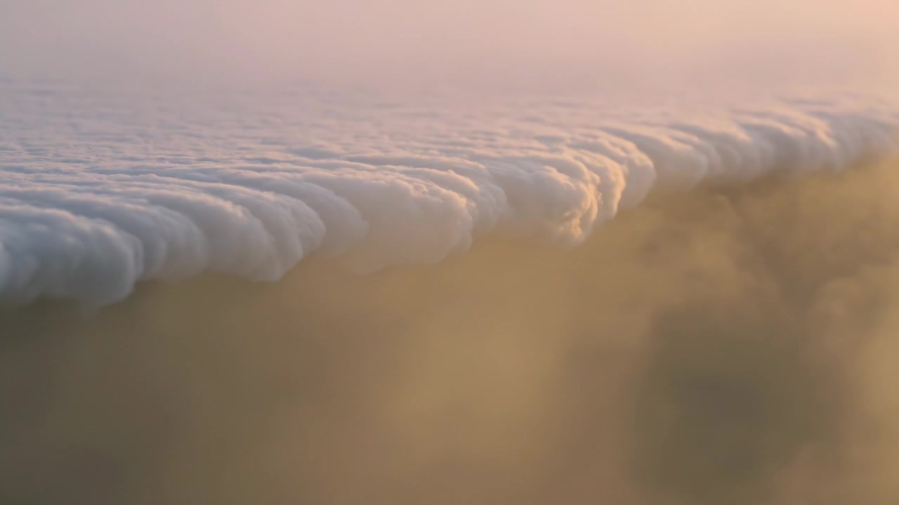 Advancing scalloped marine cloud bank moving across coast, driven by light wind and golden haze