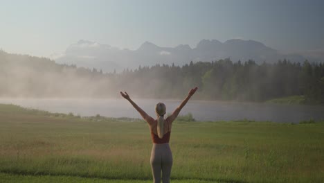 Beautiful-woman-practicing-yoga-in-early-misty-morning-of-Germany,-back-view-of-sun-salute-pose