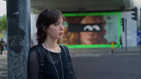 retrato de moda al aire libre de una mujer joven de estilo alternativo de pie en la calle de la ciudad de londres, reino unido, con una carretera concurrida en el fondo 2