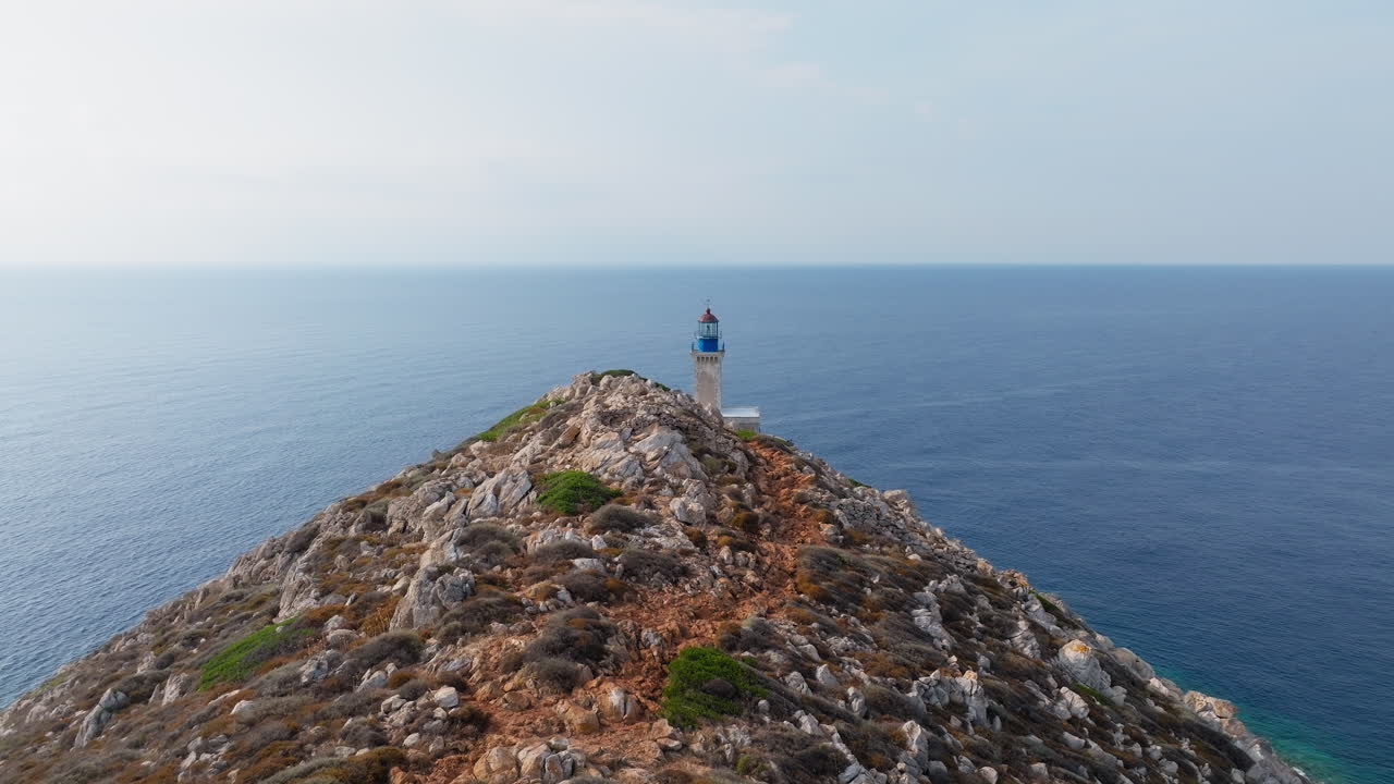 Lighthouse atop narrow rocky ridge at Cape Tainaron seen from distance against open Aegean