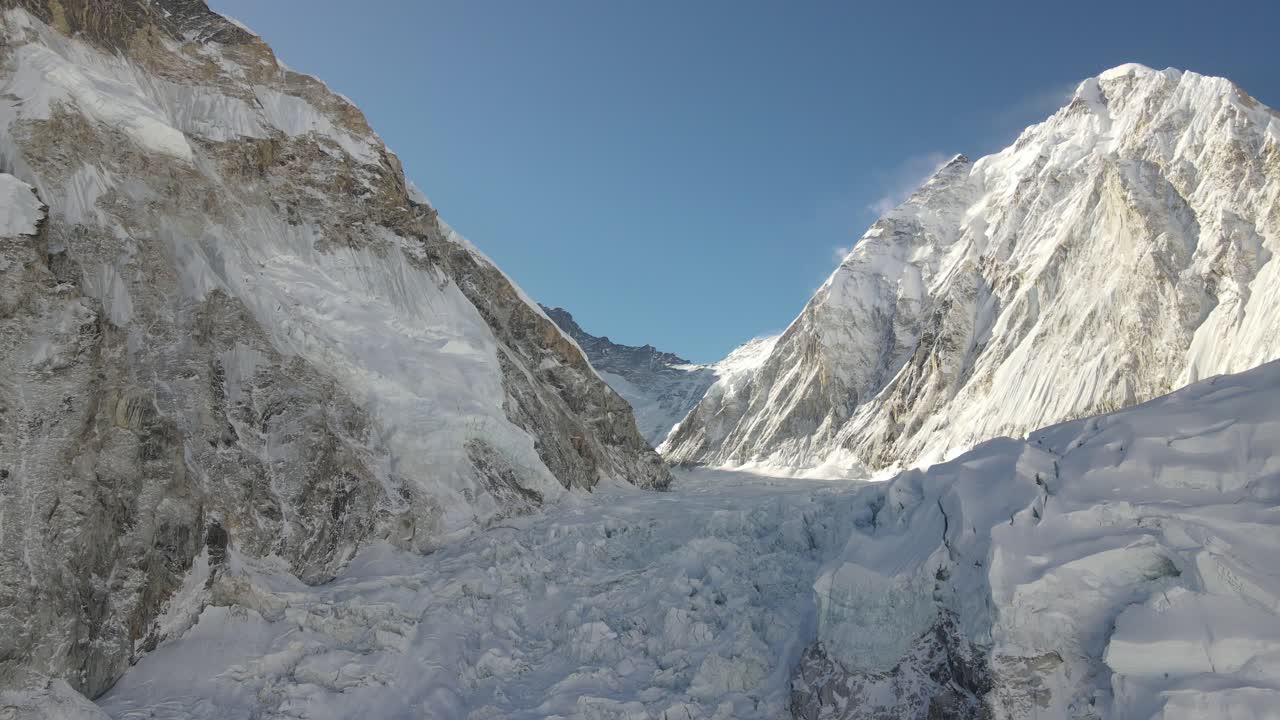 A dramatic drone shot shows the road toward Mount Everest, surrounded by glacier textures and the towering Himalaya. The high-altitude scenery reveals the raw beauty of Nepal’s rugged peaks