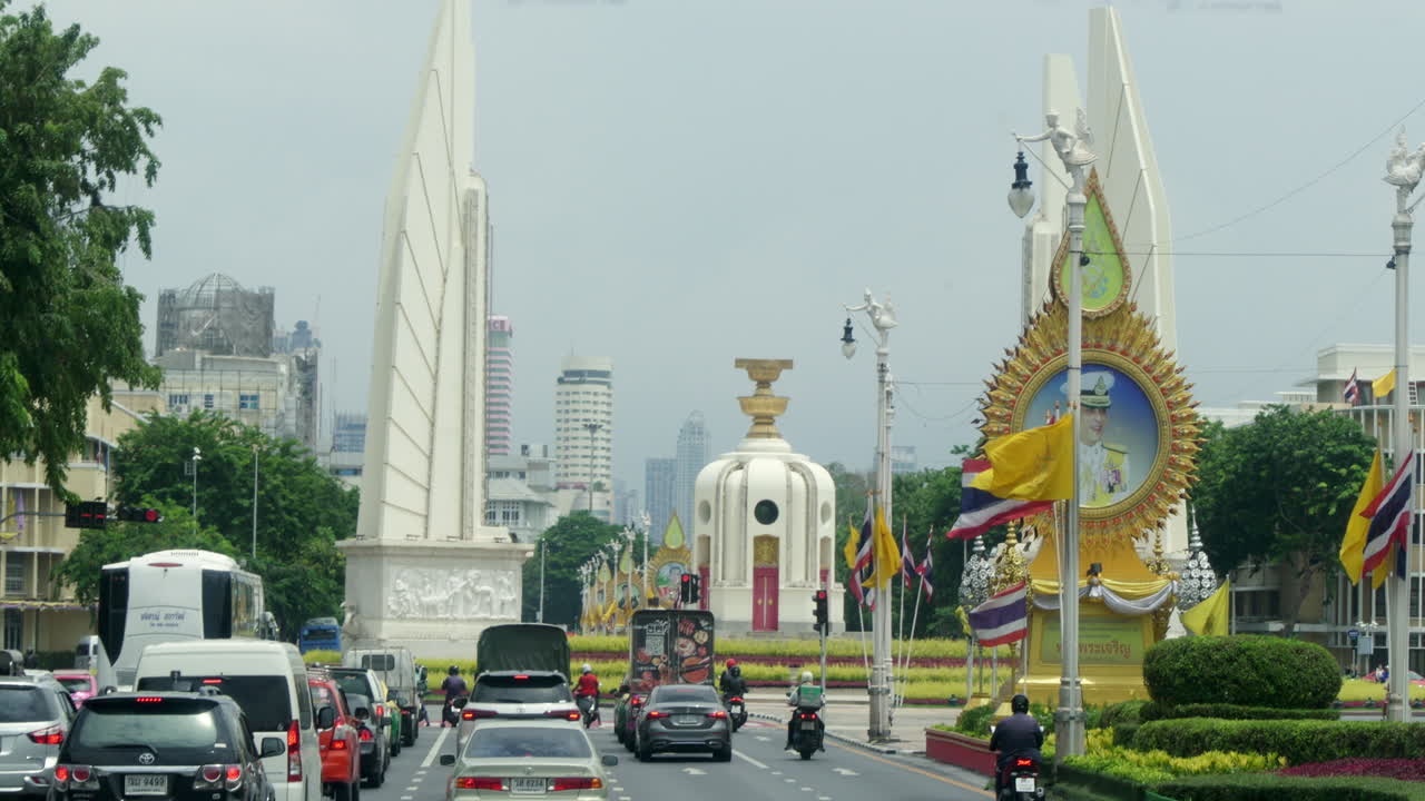Moving in a city traffic towards a roundabout and a famous landmark of Democracy Monument in the middle of Bangkok, Thailand.