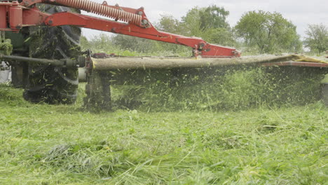 close up, lawn mower attached to tractor, machine harvesting grass