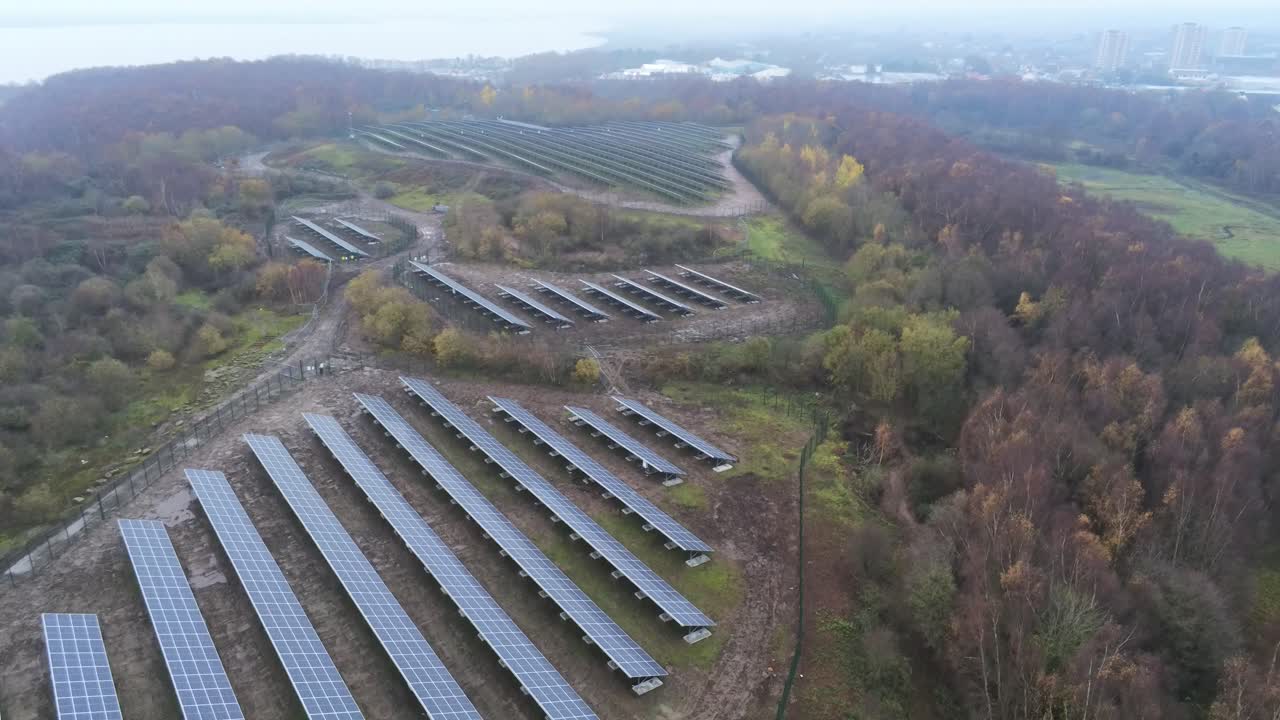 Solar panel array rows aerial view misty autumn woodland countryside descending