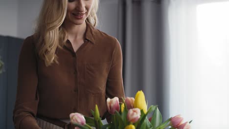 caucasian woman putting fresh tulips into the vase.