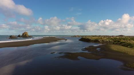 sobre la playa de arena negra whatipu y la roca ninepin, huia reserve, nueva zelanda
