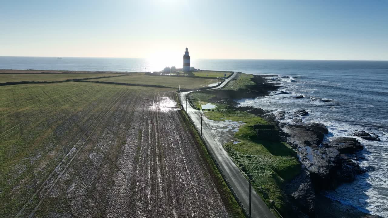Luftoptagelse i lav højde af Hook Head Lighthouse – et landskab mættet med saltvand efter en episk atlanterhavsstorm. Storslåede irske havbilleder.