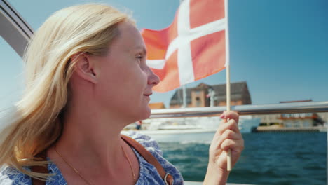 a tourist with the flag of denmark sails on a sightseeing boat through the city's canals