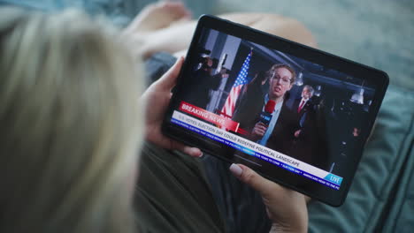 woman watching breaking news on tablet