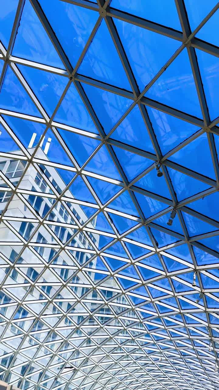 Modern glass architecture with blue sky. Unique geometric structure of glass and steel showcases a bright blue sky above a contemporary building