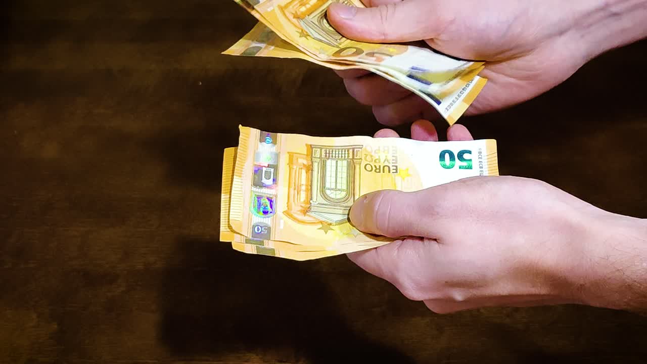 Detail mužských rukou počítajících padesátieurové bankovky
