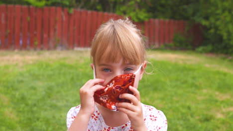 cute little girl putting on her face mask to protect against coronavirus