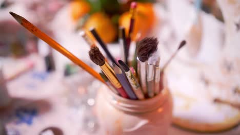 art supplies and paintbrushes in a jar