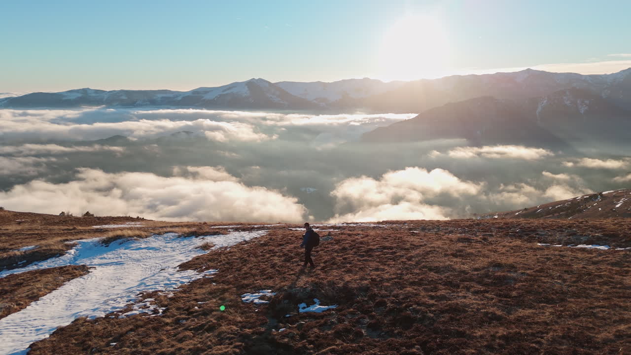 Persona che fa escursioni in montagna sopra le nuvole all'alba, in pacifica solitudine.