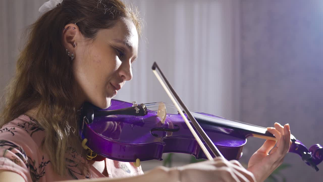 una joven violinista tocando el violín en casa, en primer plano.