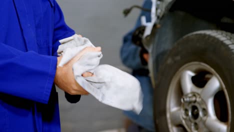 Mechanic-cleaning-hands-with-napkin-in-garage-4k