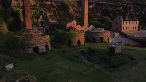 Porth-Wen-Abandonó-La-Fábrica-De-Ladrillos-Abandonados-En-La-Costa-Permanece-Amanecer-Dorado-Campo-Bahía-Vista-Aérea-Ascendente-Retroceder