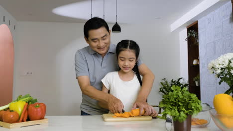 father and daughter cutting carrot.