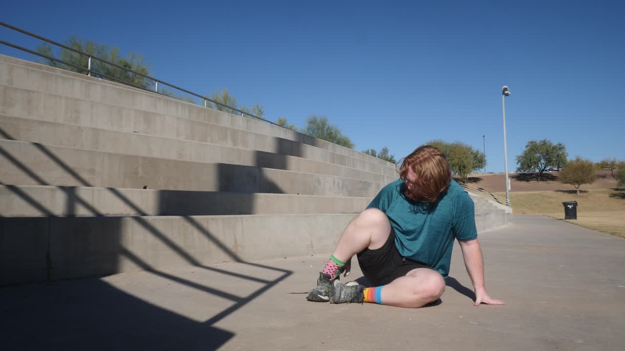 un hombre de pelo rojo se pone zapatos para correr en un parque