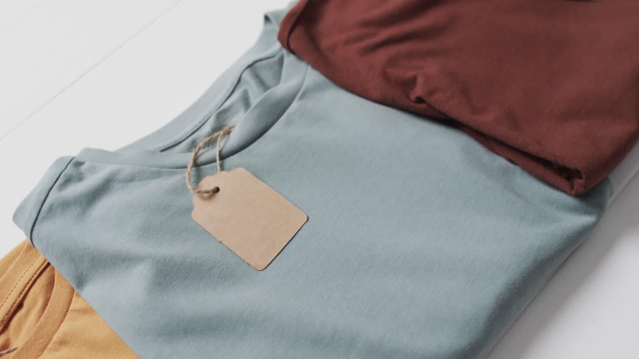video di un lay piatto di magliette multicolori con etichette e spazio di copia su sfondo bianco
