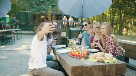 group of friends drinking wine and taking photos on phone.