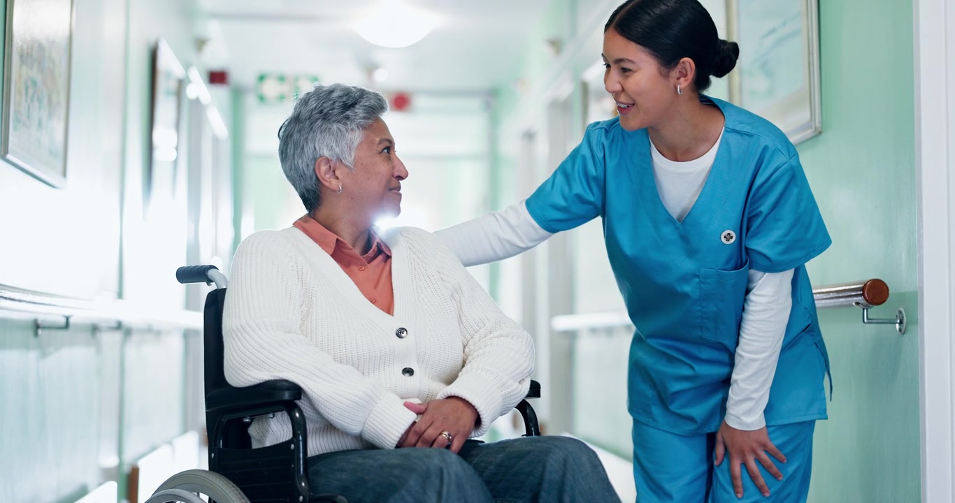 Friendly Nurse Talking to Senior Patient in Wheelchair at Hospital