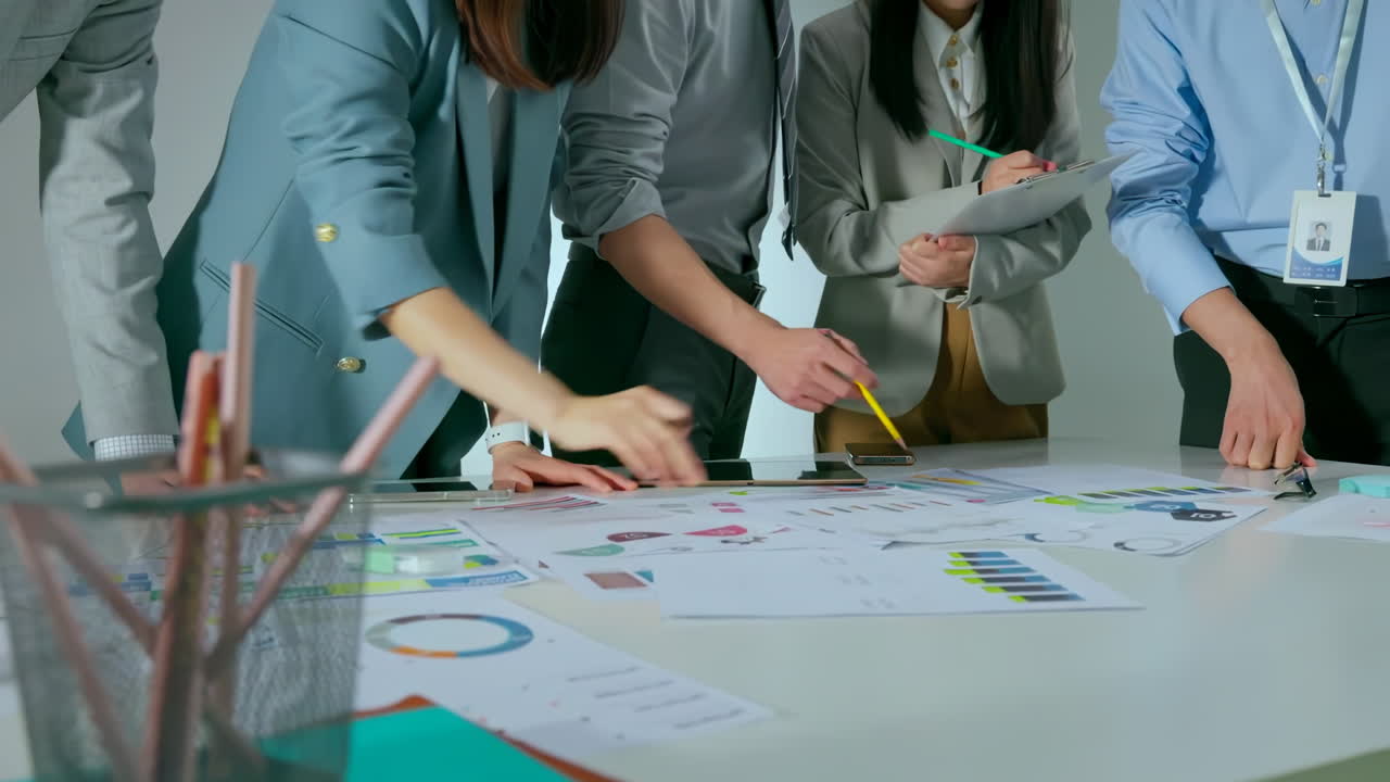 Collaborative business experts team meeting pointing at graphs and charts to analyze market data. Balance sheet, accounting, taxes, profit to discuss, plan marketing strategy, teamwork concept