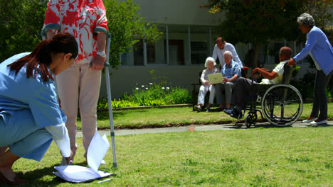 Vista-Lateral-De-Una-Doctora-Examinando-A-Un-Paciente-Mayor-En-El-Jardín-De-Una-Residencia-De-Ancianos-4k