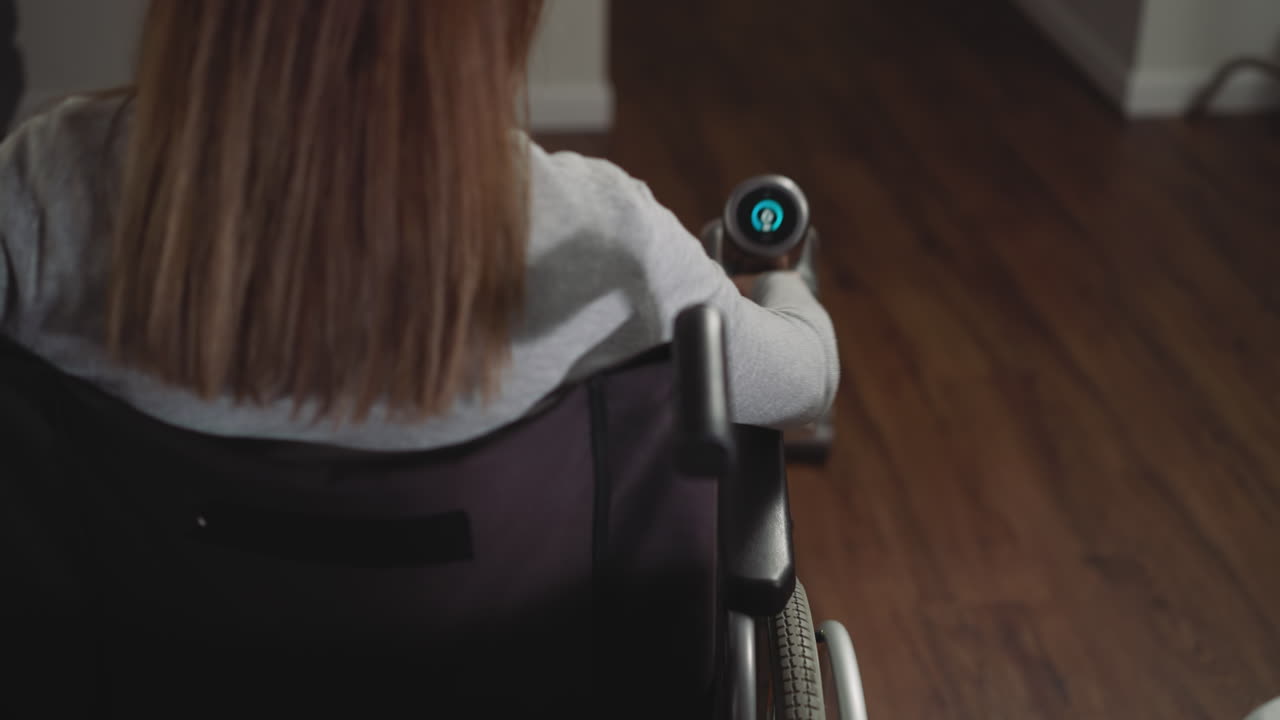 Female in wheelchair collects dust using vacuum cleaner