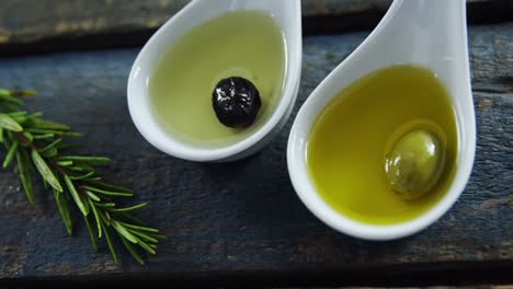 rosemary and two spoons with olive oil and olive