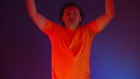 hombre loco bailando a la luz del neón de la danza ridícula. hombre gracioso en un fondo azul de color