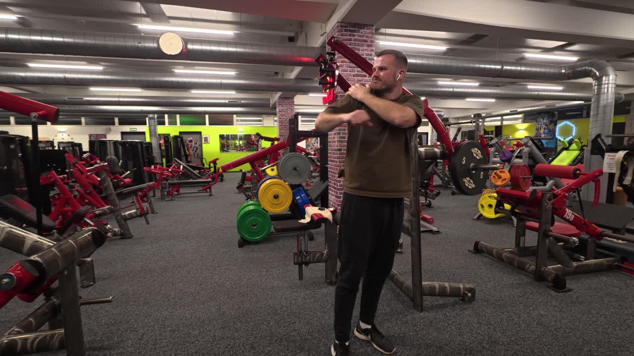 Pria memegangi bahunya setelah sesi gym yang intens, menunjukkan rasa sakit, ketegangan, dan ketidaknyamanan fisik di lingkungan kebugaran modern
